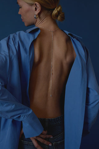 Woman wearing a mens blue button up shirt backward exposing her back and showing the sterling silver Hailey front and back chain.