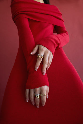 Woman wearing a red dress with her hands infront of her, showng with multiple stacked silver and gold-filled rings with white sapphire accents. 