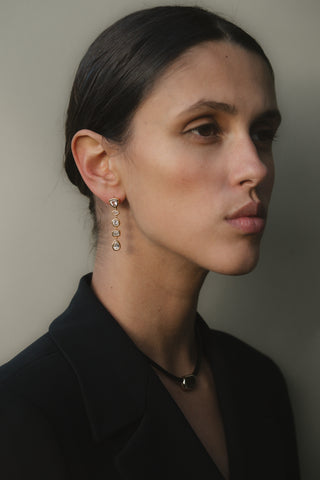Woman wearing bezel set gold tennis  earrings with a neutral background