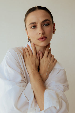 Woman wearing gold jewelry against a plain background