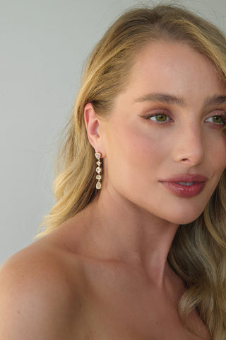 Close-up of a woman wearing tennis earrings with a plain background