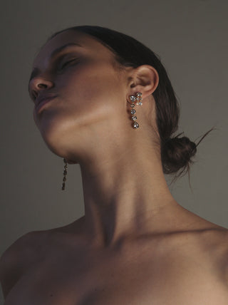Close-up of a woman wearing bezel drop earrings with a neutral background