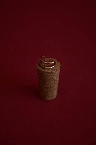 Cork with a gold ear cuff against a red background