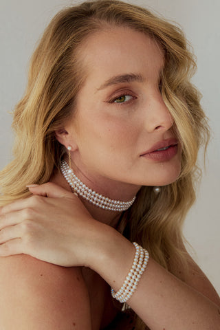 Woman wearing pearl jewelry against a neutral background