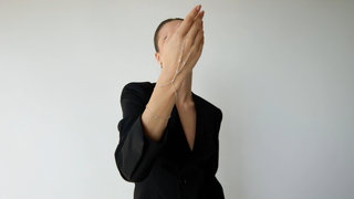 Person wearing a silver hand chain a black suit with a plain background