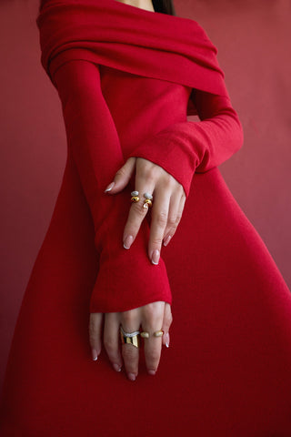 Person wearing a red dress with gold and silver stacked rings on a matching red background